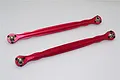 Two red anodized aluminium steering linkages with metal ball ends, positioned diagonally on a plain white background.
