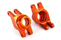 Two bright orange anodized aluminum rear stub axle carriers for a Traxxas 1/10 Maxx RC vehicle, shown from a side angle on a white background.