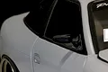 Close-up of a black racing-style side mirror mounted on a light grey RC car body shell.