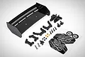 A Rovan black GT wing kit including a black plastic wing, mounting brackets, screws, nuts, body clips, and Baha 5B decal sheet.