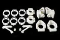 A set of white plastic RC car hub and suspension components arranged on a black background.