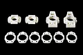 A set of white plastic RC car rear hub carriers and circular shims arranged on a black background.