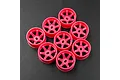 Eight fluorescent pink RC car wheel rims arranged on a dark textured surface.