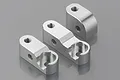 Three silver aluminium RC chassis brace mounts arranged on a grey reflective surface.