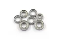 A collection of seven metal ball bearings of varying sizes arranged on a plain white background.