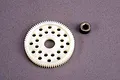 A white plastic 76T spur gear and a small metal hexagonal bushing on a grey surface.