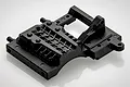 A black plastic RGT servo mount spare part for an RC vehicle, shown from a high-angle perspective on a white background.