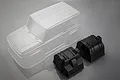MST 1/10 scale clear J4 RC crawler body shell shown with two black plastic interior or accessory components on a grey background.