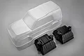 An unpainted clear polycarbonate RC crawler body shell by MST, accompanied by two black plastic inner fender liners on a grey background.