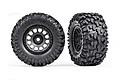 Two Traxxas Maxx all-terrain RC monster truck tires mounted on matte black wheels against a white background.