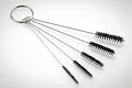 A set of five Iwata cleaning brushes of varying sizes attached to a metal keyring on a white background.