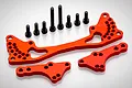 A set of red anodized aluminium RC car parts including a large shock brace and two smaller mounting plates with eight black steel screws.