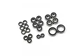 A collection of various sized metal ball bearings with black rubber seals arranged on a white background.