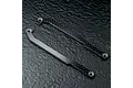 Two carbon fibre RC chassis upper deck components laid flat on a dark textured surface.