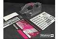 Clear unpainted Bittydesign Vision RC8B3 body shell with decal sheets and promotional card on a dark surface.