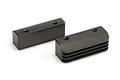 Two black metal Kyosho engine mounts with threaded holes, one featuring cooling fins, isolated on a white background.