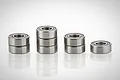 Eight metal shielded ball bearings arranged in small stacks on a white reflective surface.