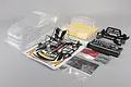 Unpainted clear polycarbonate RC car body shell kit for a Gainer Tanax GT-R NISMO R35, including plastic parts, decals, and accessories.