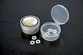 Koswork low friction X-rings and a small container of O-ring and bushing grease on a black surface.