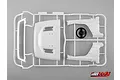 A white plastic sprue containing various 1/10 scale RC truck cab parts and a black steering wheel, set against a plain grey background.