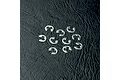 A collection of ten small silver metal E-clips scattered on a textured black surface.