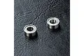 Two small metal shielded ball bearings placed on a textured black surface.