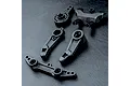 A set of black plastic RC steering assembly components including steering arms and a bridge piece on a textured black surface.