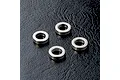 Four small silver-coloured metal bushings arranged on a textured black surface.