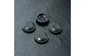 Four small black circular rubber shock seals arranged on a textured black surface.