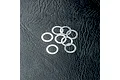 Eight thin, silver-coloured metal washers arranged on a textured black surface.