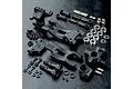 MST rear suspension arm set including plastic arms, uprights, metal shafts, bearings, and screws on a black textured surface.