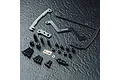 MST carbon fibre short battery mount kit with black aluminium hardware, including various screws, spacers, and mounting plates on a dark textured surface.