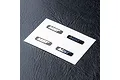 A sheet of four black MST logo decals on a white backing, placed on a textured black surface.