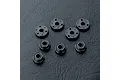 A set of four black shock pistons and four black spacers arranged on a textured black surface.