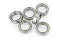 A cluster of six silver metal shielded ball bearings arranged on a white surface.