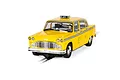 A 1/32 scale Scalextric 1977 NYC Taxi slot car in yellow, featuring a checkerboard pattern and driver figure, positioned on a slot car track.