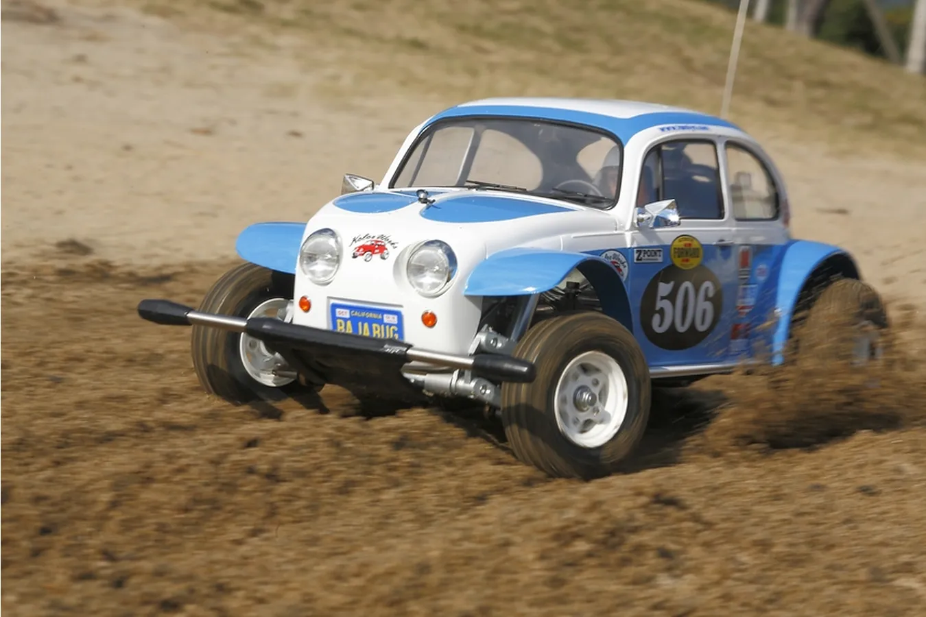 A classic Tamiya Sand Scorcher radio-controlled buggy powering through dust.