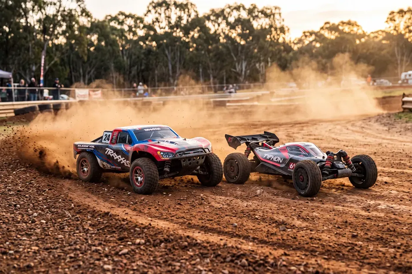 A Traxxas stadium truck and an ARRMA buggy racing side-by-side on a dusty dirt track under golden sunlight.