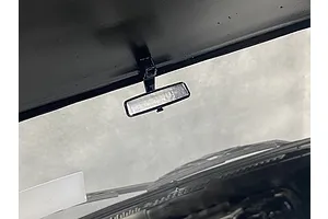 A close-up view of a small black rearview mirror mounted inside the cabin of a 1/10 scale RC car model.