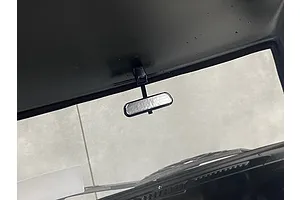 A close-up view of a small black rearview mirror mounted to the interior roof of a scale RC car body.