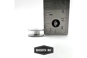 A silver aluminium winch spool for RC vehicles placed next to a metal ruler for scale, with the Reefs RC logo below.