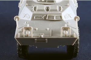 Front view of an unpainted grey plastic model of an M706 Commando armoured car against a dark background.