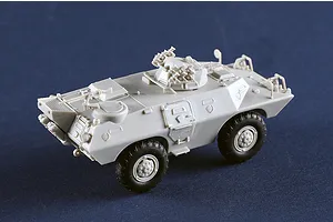 An assembled, unpainted grey plastic model of an M706 Commando armoured car on a dark blue background.