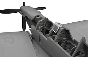 Close-up of an unpainted plastic model Spitfire cockpit showing detailed instrument panels and dual seating.