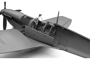 Close-up of an unassembled grey plastic model Spitfire cockpit showing interior detail and clear canopy parts.