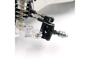 A close-up view of a black aluminium steering hub carrier installed on an RC car suspension arm, featuring a clear plastic arm and metal shock absorber.