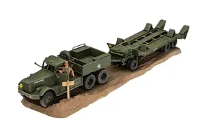 A 1/72 scale plastic model of an M19 tank transporter truck and trailer, painted in olive drab, displayed on a textured brown base.