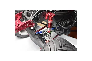 A close-up view of a red GPM Racing aluminium shock absorber installed on an RC vehicle chassis.