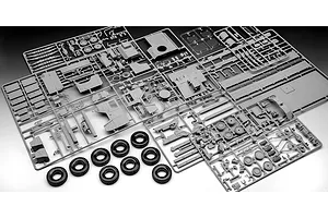 Multiple grey plastic model kit sprues and eight black rubber tires for a 1/35 scale military truck model.