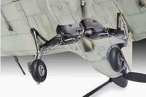 Close-up view of the underside of a plastic model aircraft showing the landing gear, wheel wells, and propeller.